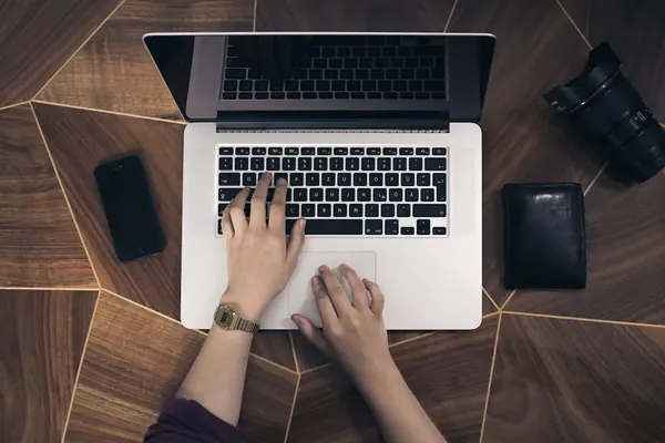 Hands typing on a laptop at a wooden desk for the guide on press releases and SEO