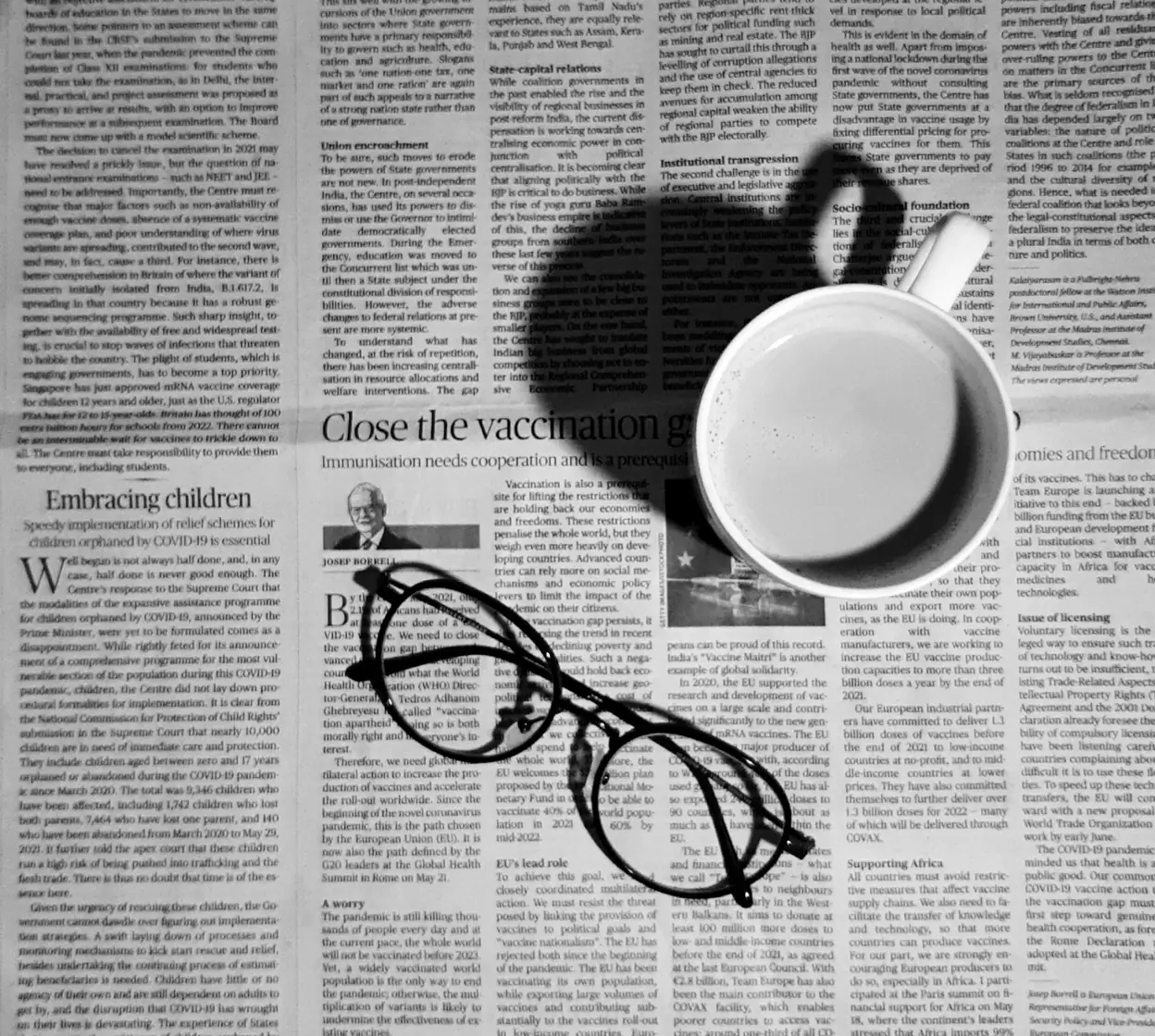 Newspaper with a cup of coffee and reading glasses, representing verified media coverage